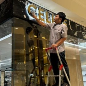 IK Services staff on a ladder cleaning a shop sign