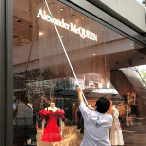 IK Services professional cleaner using a long pole to clean the exterior glass of an Alexander McQueen store