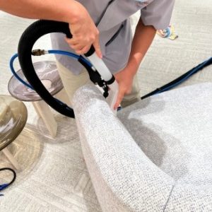 Close-up of a IK Services staff using a vacuum to clean upholstery